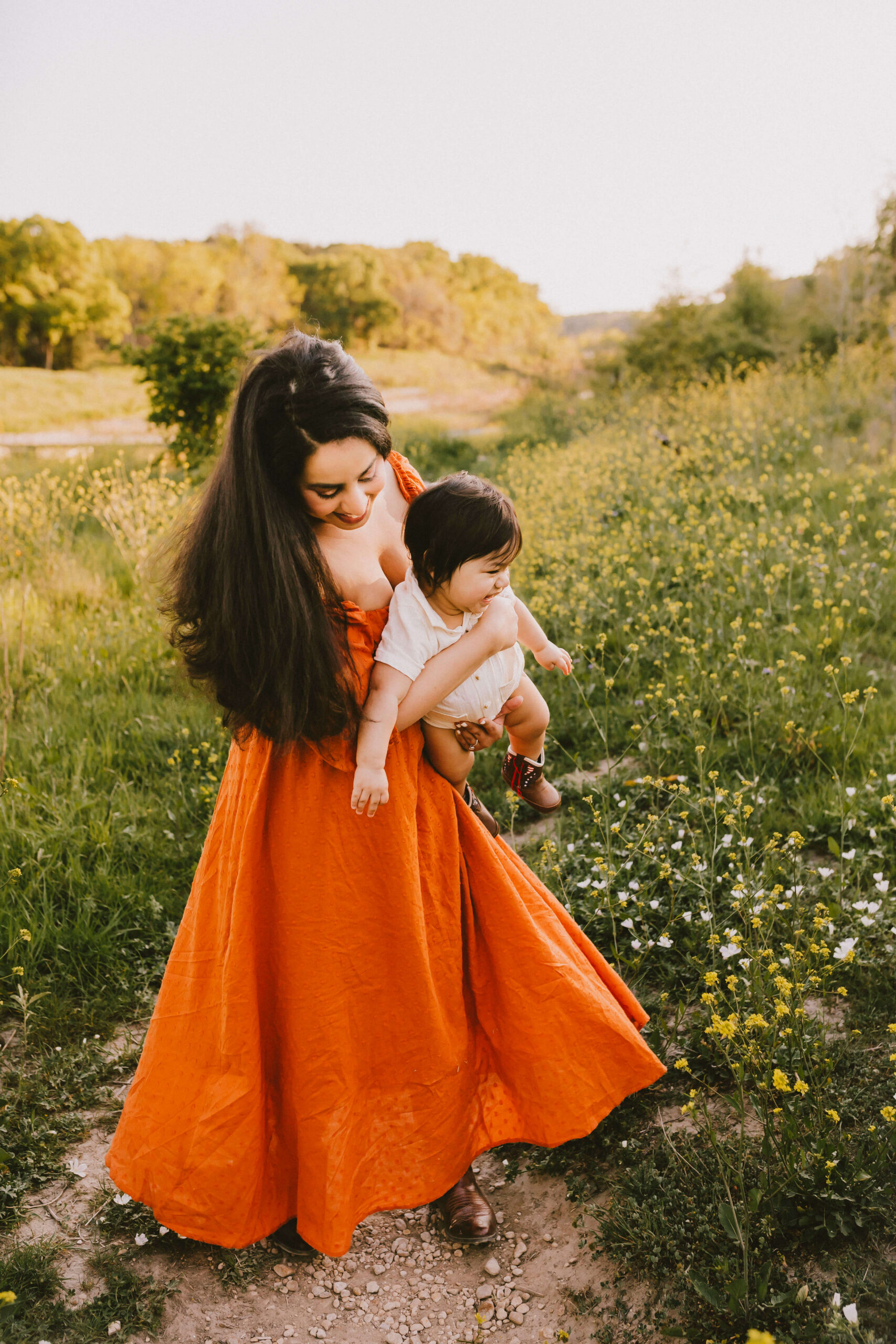 Dr. Vargas smiles while holding her baby in an open field.