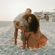 Dr. Vargas on the beach with her family, smiling and hugging. Contact today to learn more about Marigold Pediatrics.